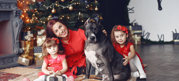 a famil posing for a photo with their dog on Christmas