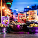 Three cans of Frommbo Gumbos with bowls of pet food on a city street at night.