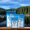 Fromm pet food packages on a wooden platform with a scenic background of trees and water.