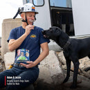 Man in search and rescue gear with a black dog, holding Nulo dog food packaging, with 'Adam & Jessie Arizona Search Dogs Team' text.