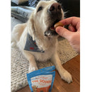 Dog eating a treat with a package of 'The Dough' in the foreground