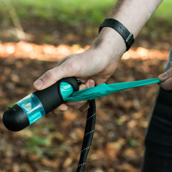 Person holding a teal and black tool with a blurred natural background