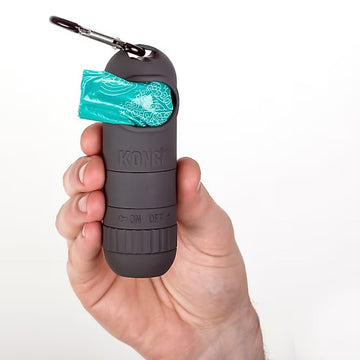 Hand holding a K9 One dog training clicker with a teal cover on a white background