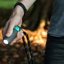Hand holding a flashlight with a blurred natural background