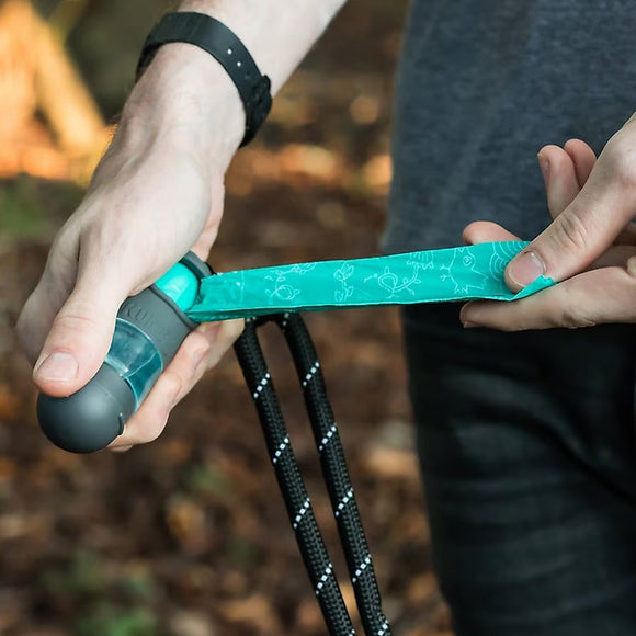 Person holding a teal and black tool with a blurred natural background