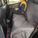Person sitting on a car seat with a gray quilted cover, wearing a yellow shirt and black pants.