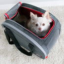 Small white dog peeking out from a gray pet carrier with red interior on a light carpet.