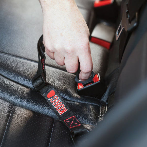 Hand fastening a black seat belt with red branding on a car seat.