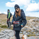 Woman in outdoor clothing with a dog on a leash in a rocky landscape