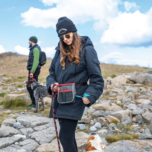Woman in outdoor clothing with a dog on a leash in a rocky landscape