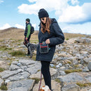 Woman walking a dog on a rocky path with mountains in the background