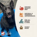 Black dog sitting on a blue mat with Aline pet food brand information on the side.