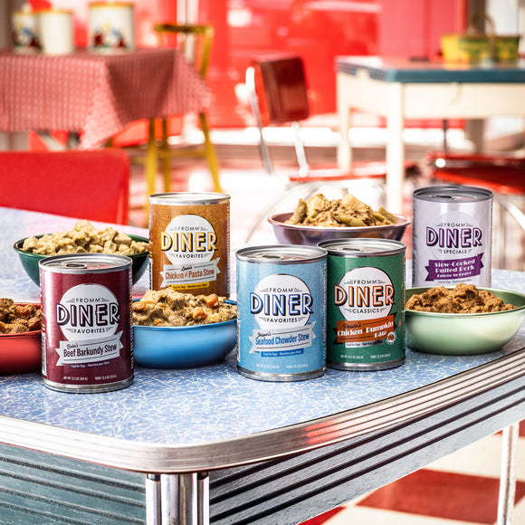 Cans of Diner brand food products on a table with a retro diner setting in the background.