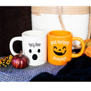 Two mugs, one white with a ghost design and 'hey boo' text, the other orange with a pumpkin face and 'good morning pumpkin' text, on a textured surface with pumpkins and leaves.