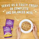 Stella & Chewy's Carnivore Cravings pet food packages with a bowl of food on a wooden surface.