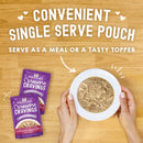 Stella & Chewy's Carnivore Cravings pet food pouches with a bowl of food on a wooden surface.