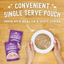 Stella & Chewy's Carnivore Cravings pouches with a bowl of food on a wooden surface.