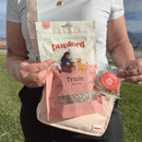 Person holding a package of Pupford dog treats in an outdoor setting