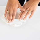 Two hands with gold rings on a white surface