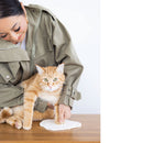 Woman in a green jacket with an orange cat on a wooden table