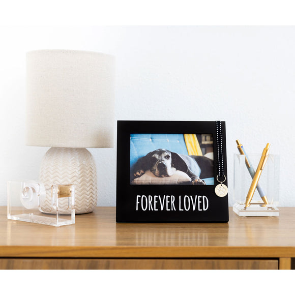 Decorative photo frame with a dog picture and 'Forever Loved' text on a desk.