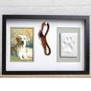 Framed artwork of a dog, leather leash, and handprint on a white wall.