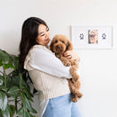 Woman holding a brown dog next to a wall with paw prints and a photo of the dog.