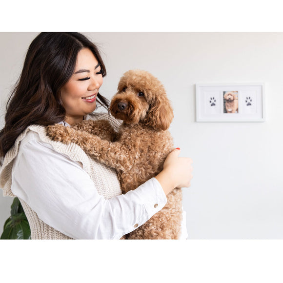 Woman holding a brown dog with a photo frame in the background