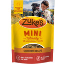 Zuke's Mini Naturals dog treat package with a woman and two dogs in the background.