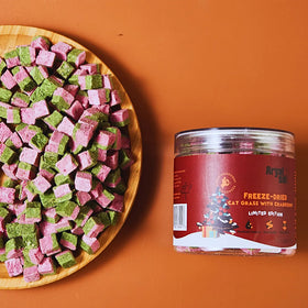 Freeze-dried cat grass with cranberries on a wooden plate next to a red container on an orange background