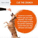 Dog reaching up to a hand holding a treat with text about crunchy treats on a white background.