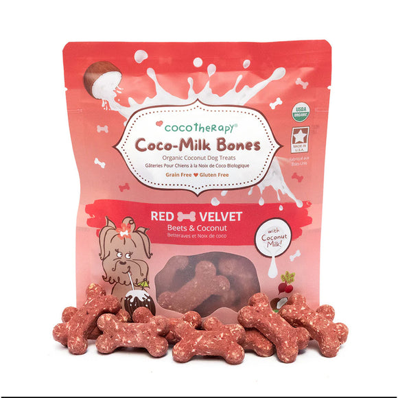 Red velvet dog treats with 'CocoTherapy Coco-Milk Bones' packaging on a white background