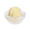 Glass bowl with yellow butter on a white background