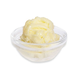 Glass bowl with yellow butter on a white background