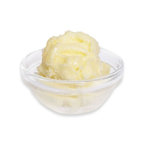 Glass bowl with yellow butter on a white background