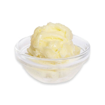 Glass bowl with yellow butter on a white background