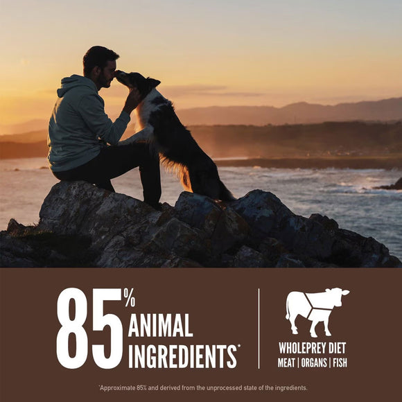 Man and dog sitting on rocks by the ocean at sunset with a product label about animal ingredients.