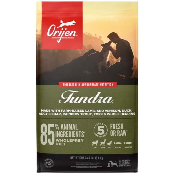 Orijen Tundra dog food package with a silhouette of a person and dogs against a sunset background.