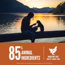 Person and dog sitting on a log by a lake at sunset with promotional text about animal ingredients.