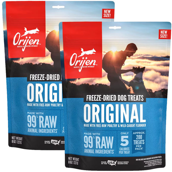 Two packages of Orijen freeze-dried dog treats with a sunset background