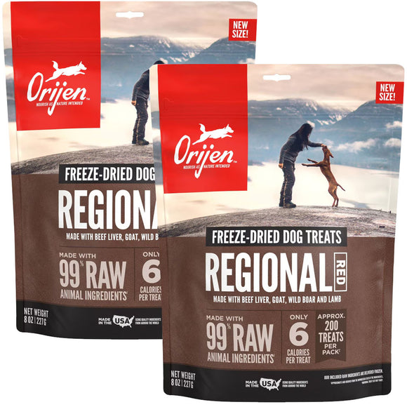 Two packages of Orijen freeze-dried dog treats with mountain and person background