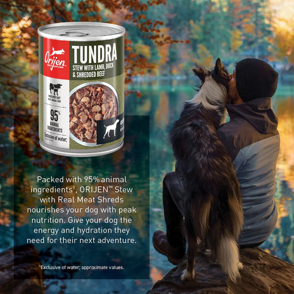 Orijen Tundra can of dog food with a person and dog by a lake