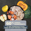 Pet food with ingredients including fish, carrots, and a pumpkin, surrounded by vegetables on a dark background.