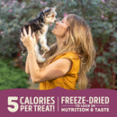 Woman holding a small dog outdoors with promotional text about freeze-dried treats.