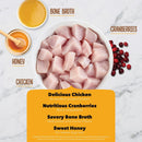Ingredients for a pet food product including chicken, cranberries, bone broth, and honey on a marble background.