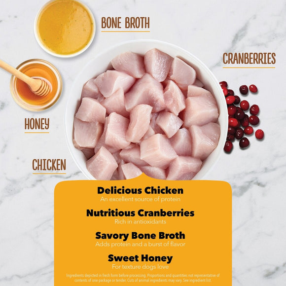 Ingredients for a pet food product including chicken, cranberries, bone broth, and honey on a marble background.