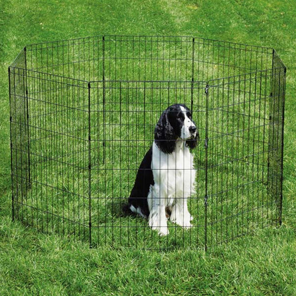 Dog inside a black metal pet playpen on grass