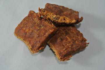 Three pieces of brown, crumbly food on a gray background
