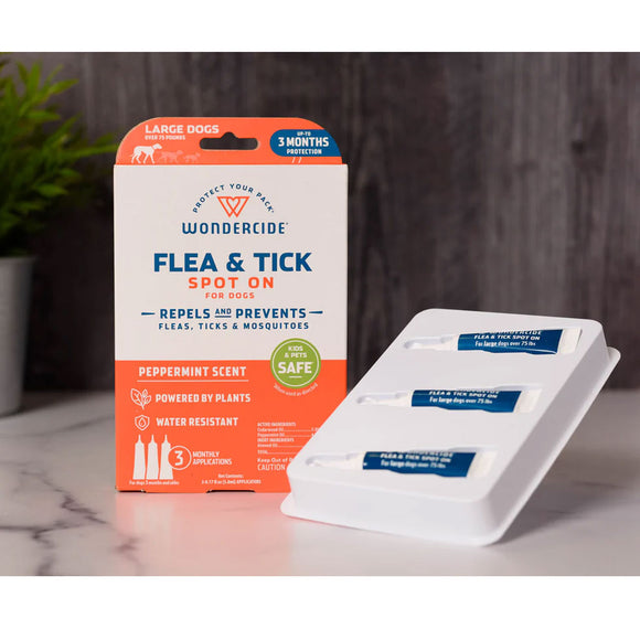Wondercide flea and tick spot on for dogs packaging with spot on containers on a marble surface.