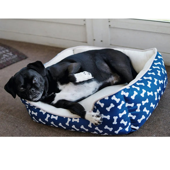 Black and white dog lying on a blue pet bed with white bone pattern